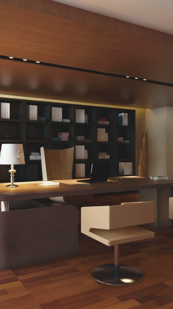 A sophisticated workspace showcasing the principles of luxury executive office design interiors through layered, warm lighting. The room features a custom dark wood desk illuminated by a striking traditional desk lamp with a detailed shade, providing focused task lighting, while minimalist black recessed track lights overhead cast soft ambient illumination. In the background, floor-to-ceiling dark wooden built-in shelves are subtly lit by warm integrated accent LEDs, emphasizing texture and depth. A sleek high-backed leather executive chair and a contemporary low-profile guest armchair complete the workspace layout, highlighting a calm, authoritative atmosphere free of harsh shadows.