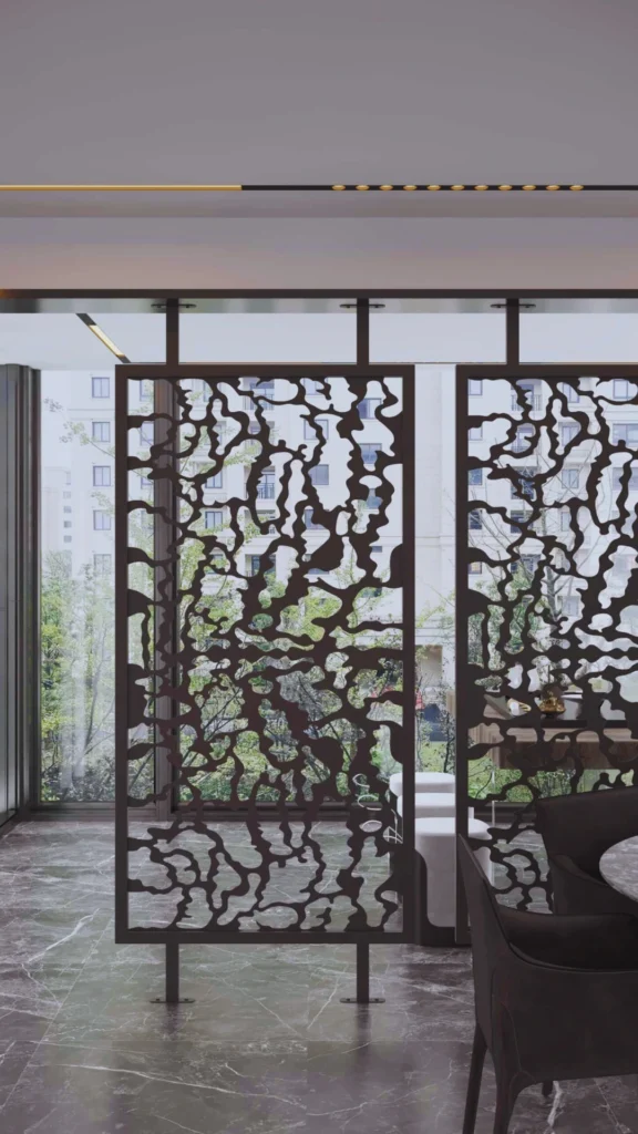 A traditional luxury Chinese interior showcasing an elegant, dark-framed wooden folding room divider. The multi-panel screen features beautiful, hand-painted panels depicting delicate white and red floral blossoms on branches against a warm, metallic gold background. The screen is positioned to create a layered, private nook within a large, brightly lit room with a classic dark wood table and chairs nearby.