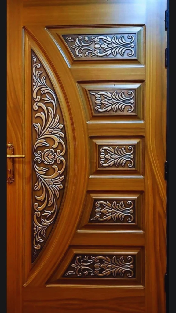 A striking luxury door showcasing a masterful combination of authentic materials. The solid golden-brown wood door features highly detailed, metallic silver or pewter panels inlaid with intricate, hand-finished floral and leaf filigree scrollwork. A classic polished brass handle complements the contrasting warm wood grain and textured metal inserts, perfectly illustrating how mixed materials add layers and depth to premium door design.